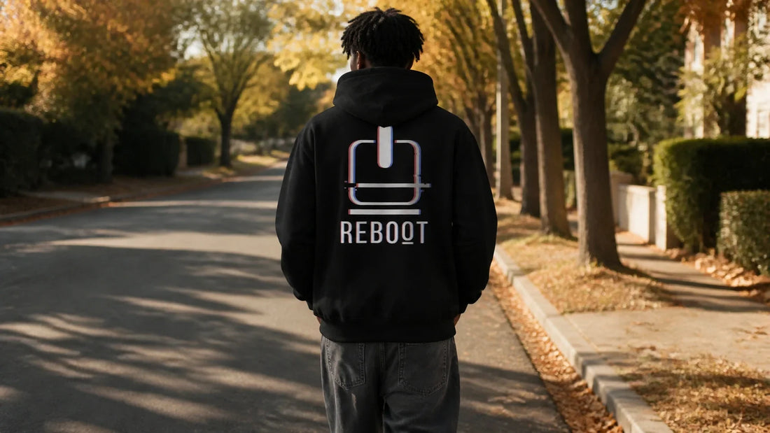 Person wearing the NO.925 Reboot Oversized Graphic Hoodie in vintage black on a tree-lined fall street