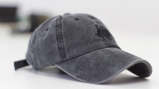 A single faded black distressed dad hat with worn brim resting on a light surface