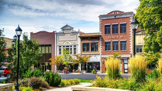 Small town main street with brick buildings, lampposts, and tree-lined sidewalks in summer