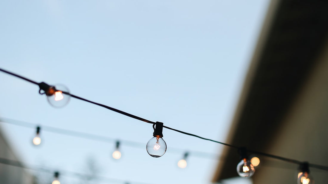 String lights stretched against a dusk sky, the kind that illuminate a backyard at night
