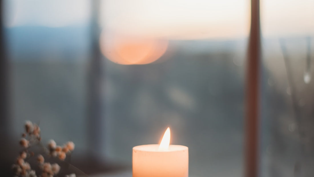 Lit candle on a windowsill at golden hour, soft warm light