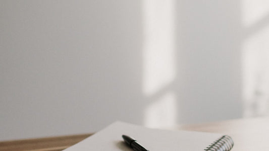 Open notebook with a pen on a wooden desk, soft morning light