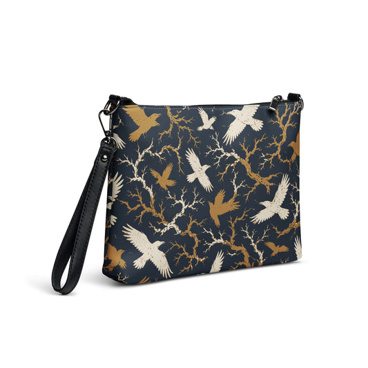 Faux leather crossbody bag with all-over cream and gold raven and bare branch print on navy background, dark gray hardware, front view
