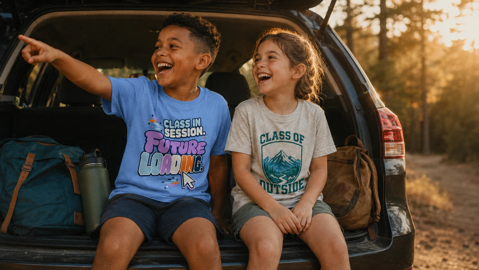 Two children on a car tailgate wearing NO.925 Future Loading and Class of Outside kids tees