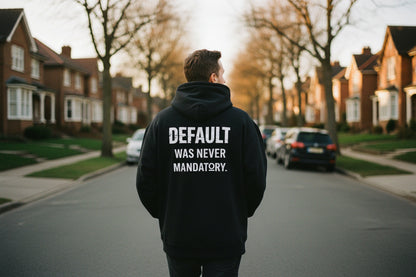 The Default Was Never Mandatory oversized graphic hoodie in black, back view showing bold white statement typography across upper back, dropped shoulder oversized silhouette.