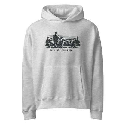 Parent and child at a fence looking over a mountain road, The Lane Is Yours Now oversized graphic hoodie