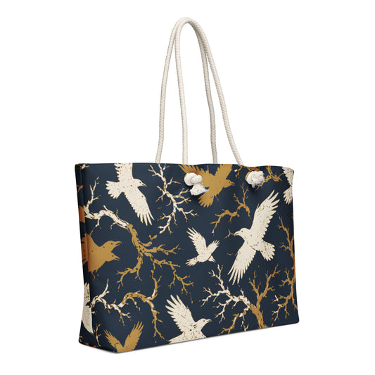 White strap oversized weekender bag with all-over cream and gold raven and bare branch print on navy background, cotton rope handles, front view