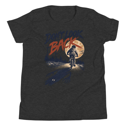 Don't Look Back youth t-shirt with a child riding a bicycle at sunset while a long clawed shadow follows on the road in dark grey heather, front view