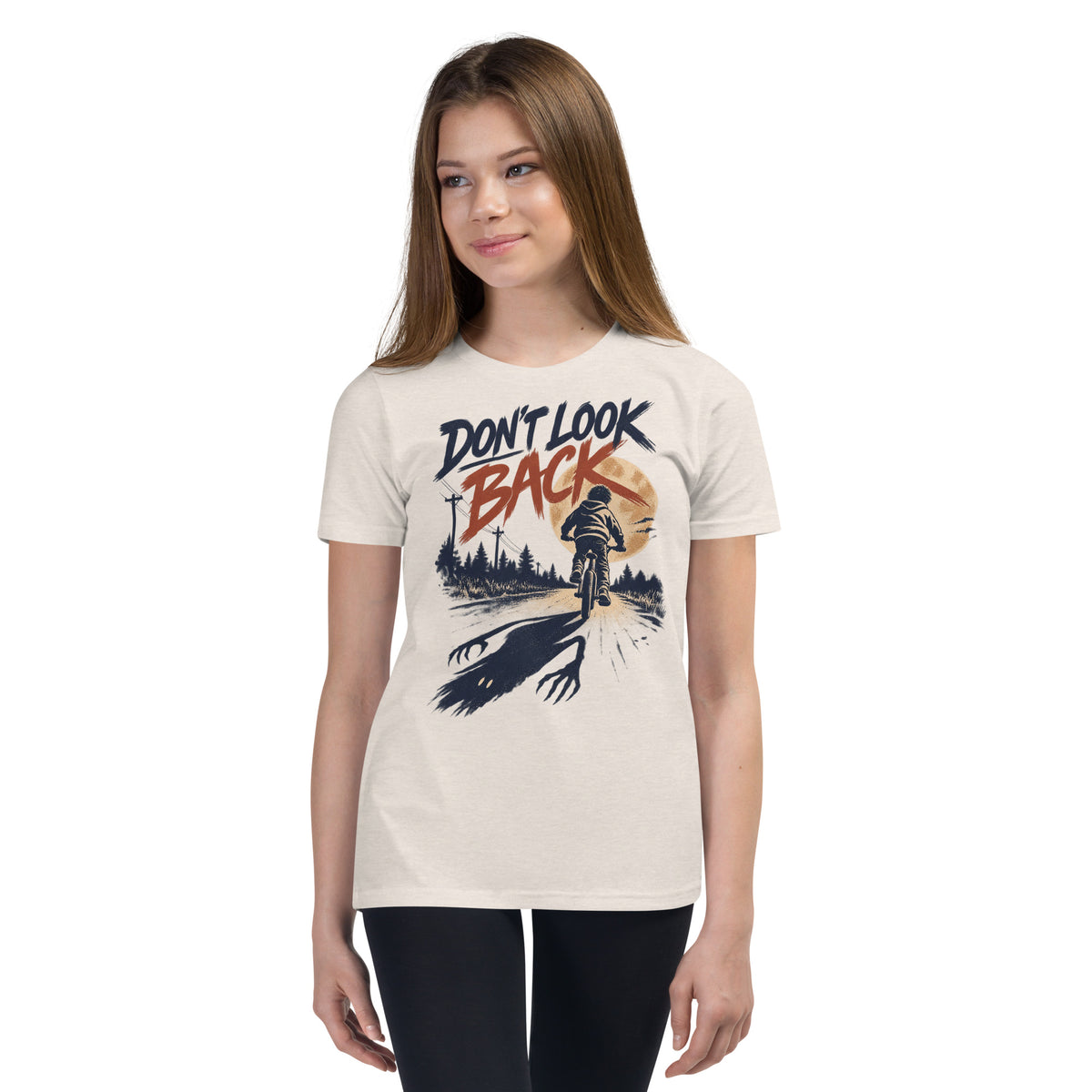 Don't Look Back youth t-shirt with a child riding a bicycle at sunset while a long clawed shadow follows on the road in heather dust, front view